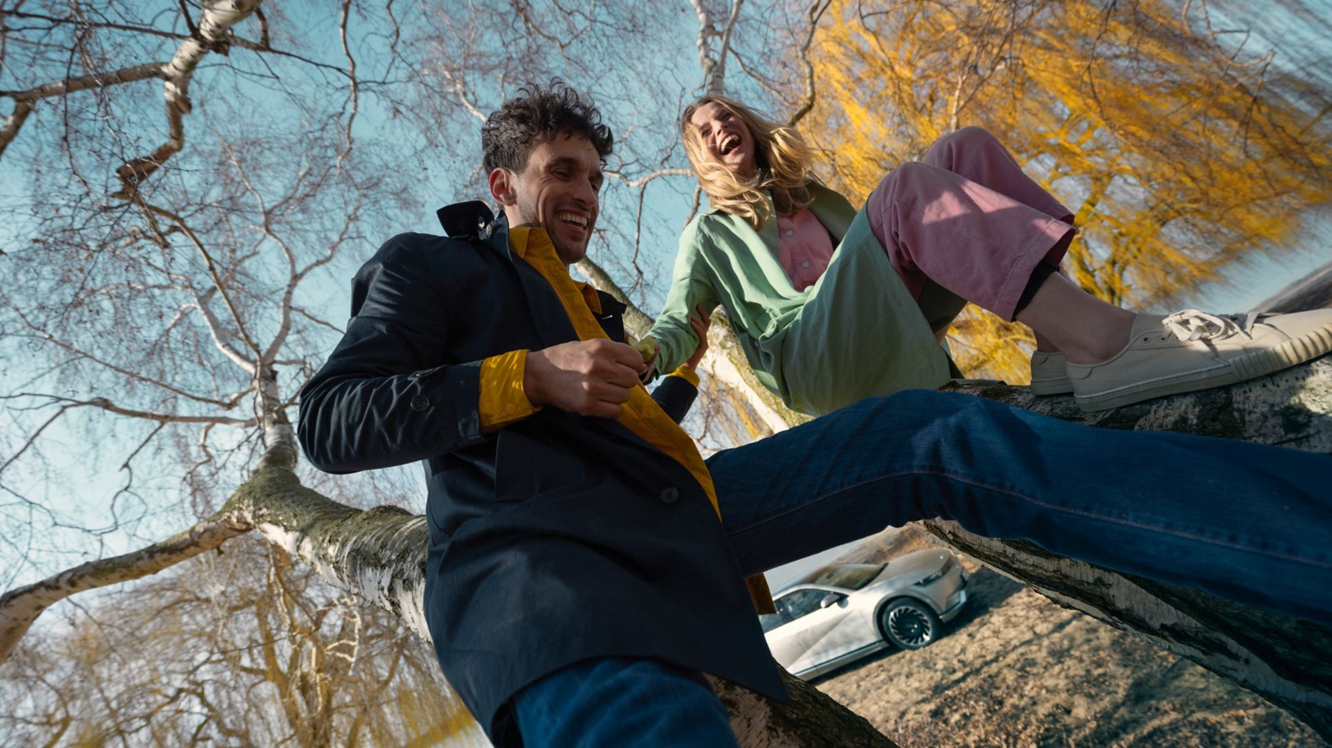 A man about to cross the road to get to his parked Hyundai IONIQ. He holds a smartphone in his hand.