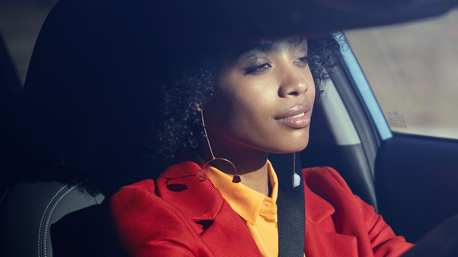A woman sitting behind the wheel of her Hyundai KONA, looking very relaxed.