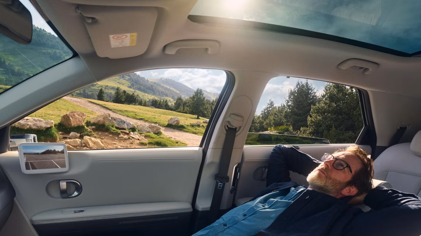 Man in the passenger seat watching the sky through the sun roof of a Hyundai.
